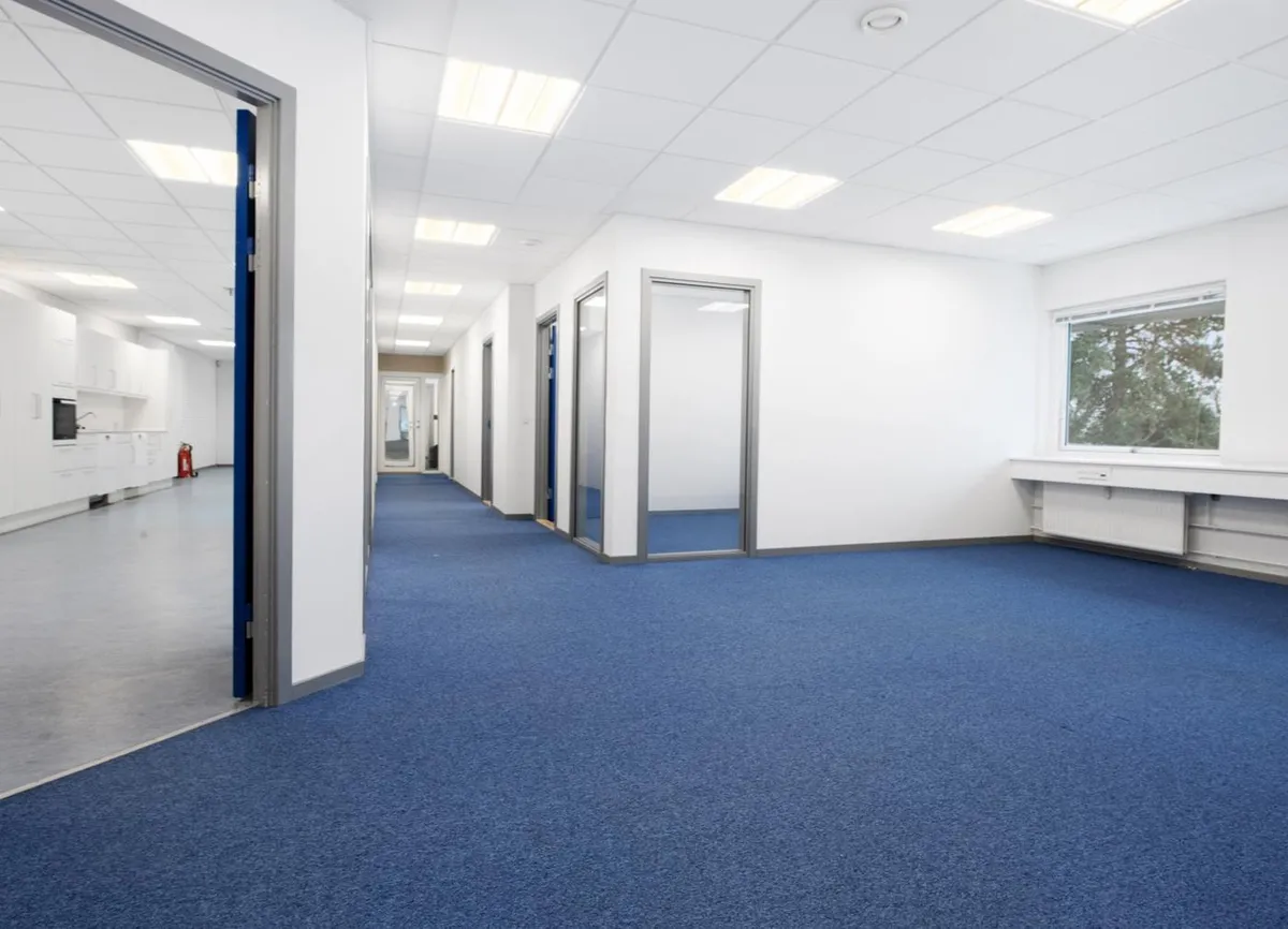 Kontorlokaler med hvide vægge og lysegult gulv og gulvbelægning i blåt og lyseblåt med spejle og vinduer og indbygget