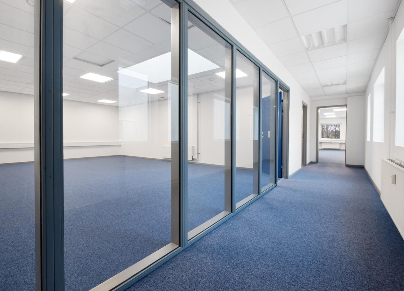 Store lokaler med glasvægge, højt gulv og hvide vægge og lofter