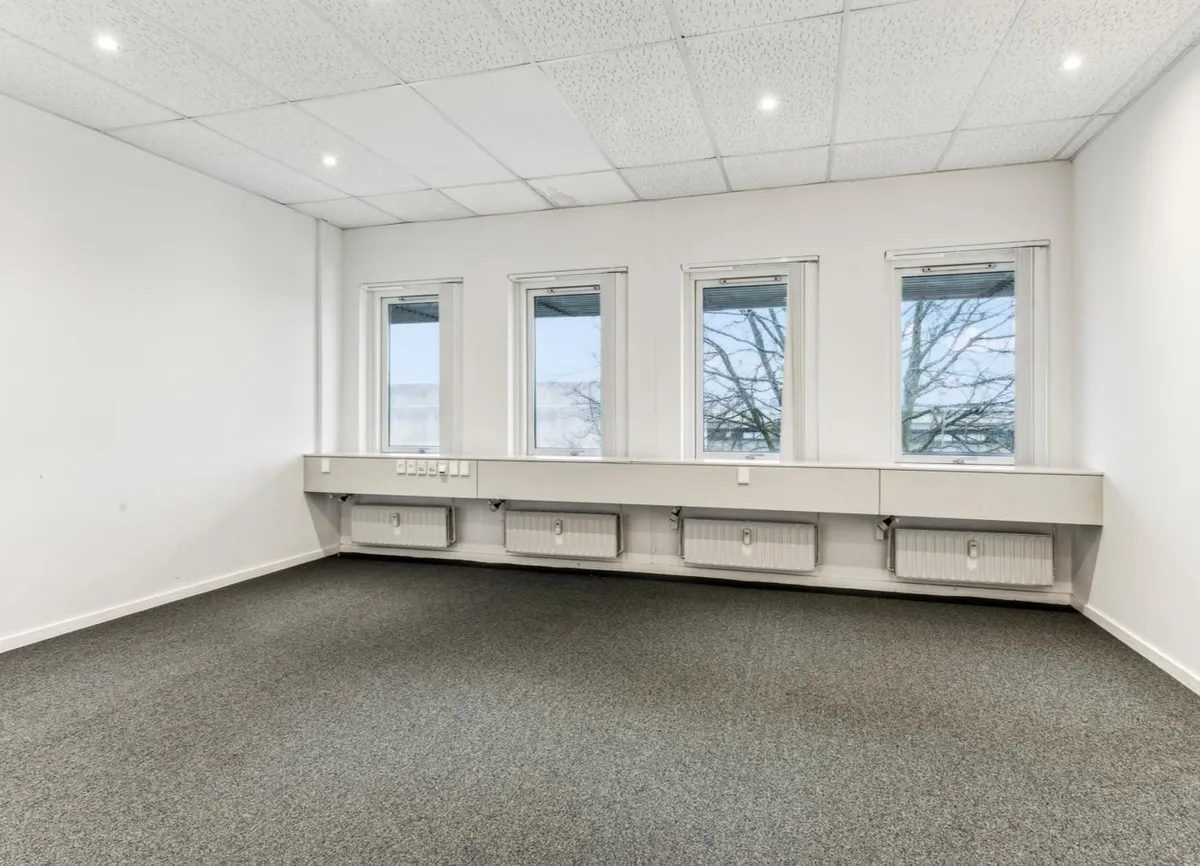 Kontor med fire vinduer og radiatorer under, moderne og velplejet design, lyst og rummeligt