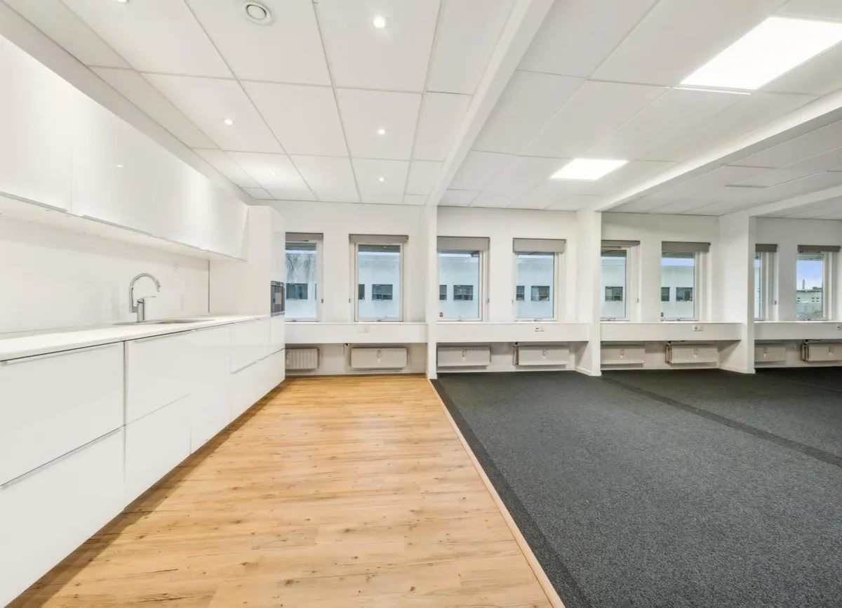 Køkken med hvide vægge, lyse lofter, lyse gulvbelægning og lyse vinduer med udsigt til gaden