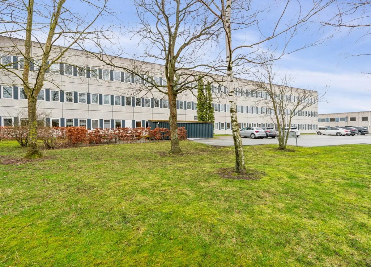 Kontorbyggeri i Skovlunde med grønne områder og parkeringsplads for biler