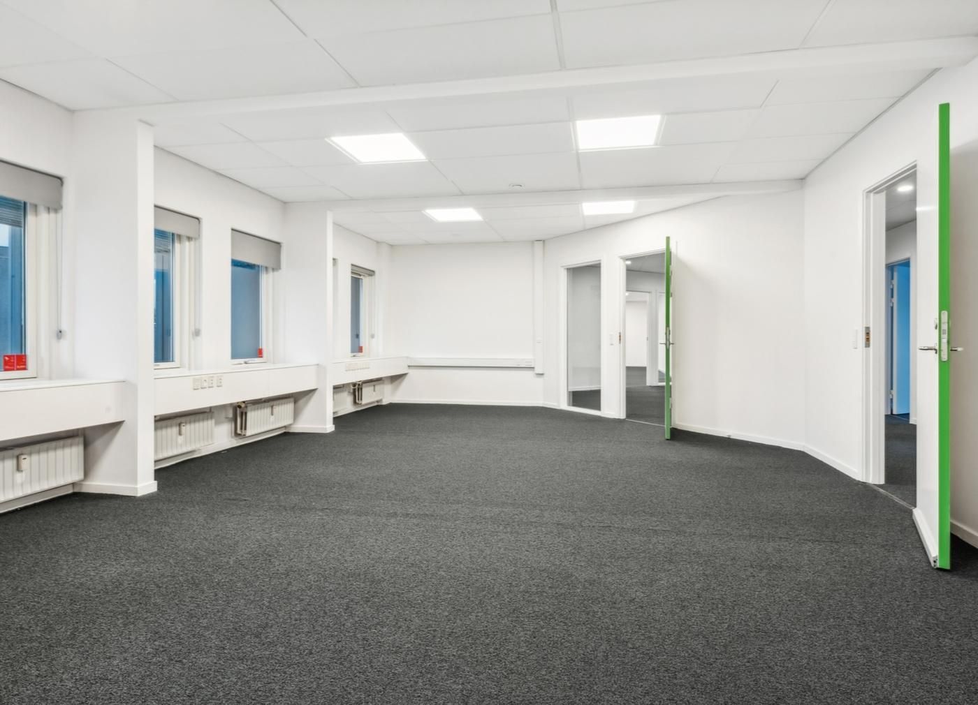 Kontorlokaler med hvide vægge, lyse gulvbelægning og vinduer, som giver eksempel på et nyt, funktionelt og teknologisk