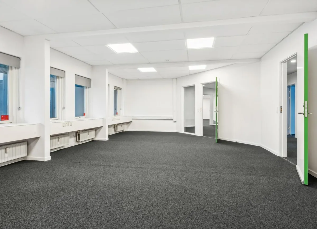 Kontorlokaler med hvide vægge, lyse gulvbelægning og vinduer, som giver eksempel på et nyt, funktionelt og teknologisk