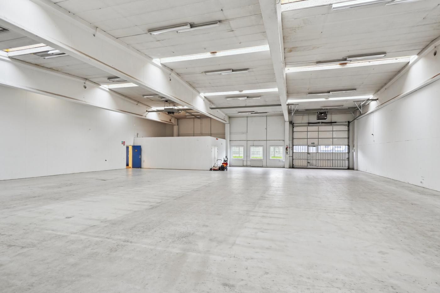 Lagerlokale med hvid maling, lysekroner, gulv, garagedør og kørestolsrampe