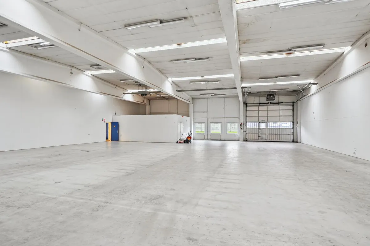 Lagerlokale med hvid maling, lysekroner, gulv, garagedør og kørestolsrampe