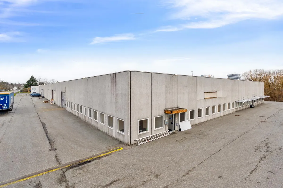 Lager og kontorlokaler i luksuriøs bygning med moderne design, flere vinduer og trækant på facaden, hvor en lastbil parkeret