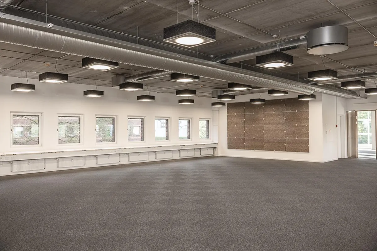 Rummeligt kontor med højt loft, lysekroner, tæppegulv og store vinduer med udsigt til haven