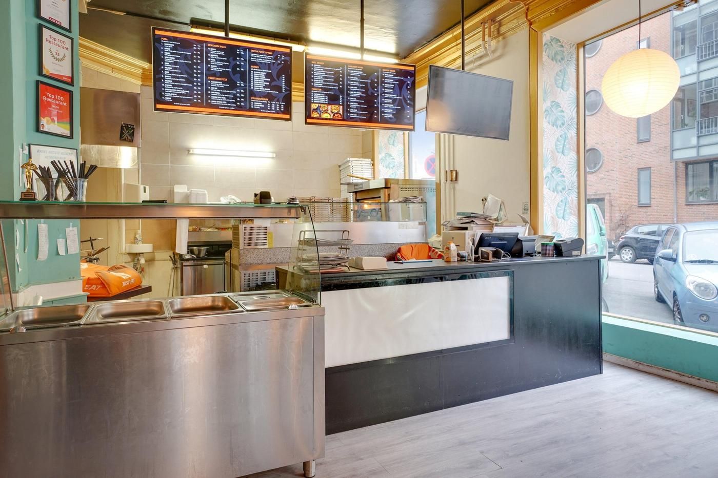 Indvendigt i en pizzeria med bord, servietholder, bøfler, briller, spisestue og spisestuebord med køkkenudstyr, meny, stol