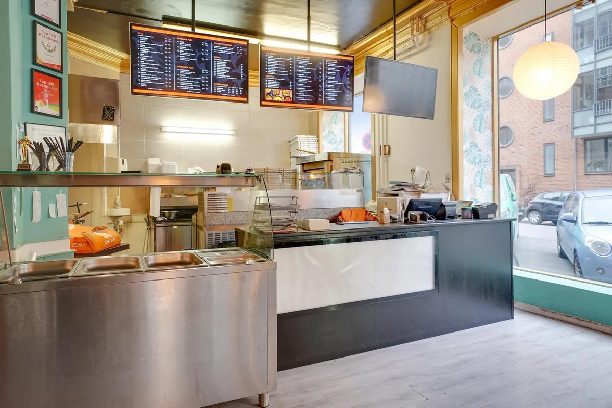 Indvendigt i en pizzeria med bord, servietholder, bøfler, briller, spisestue og spisestuebord med køkkenudstyr, meny, stol