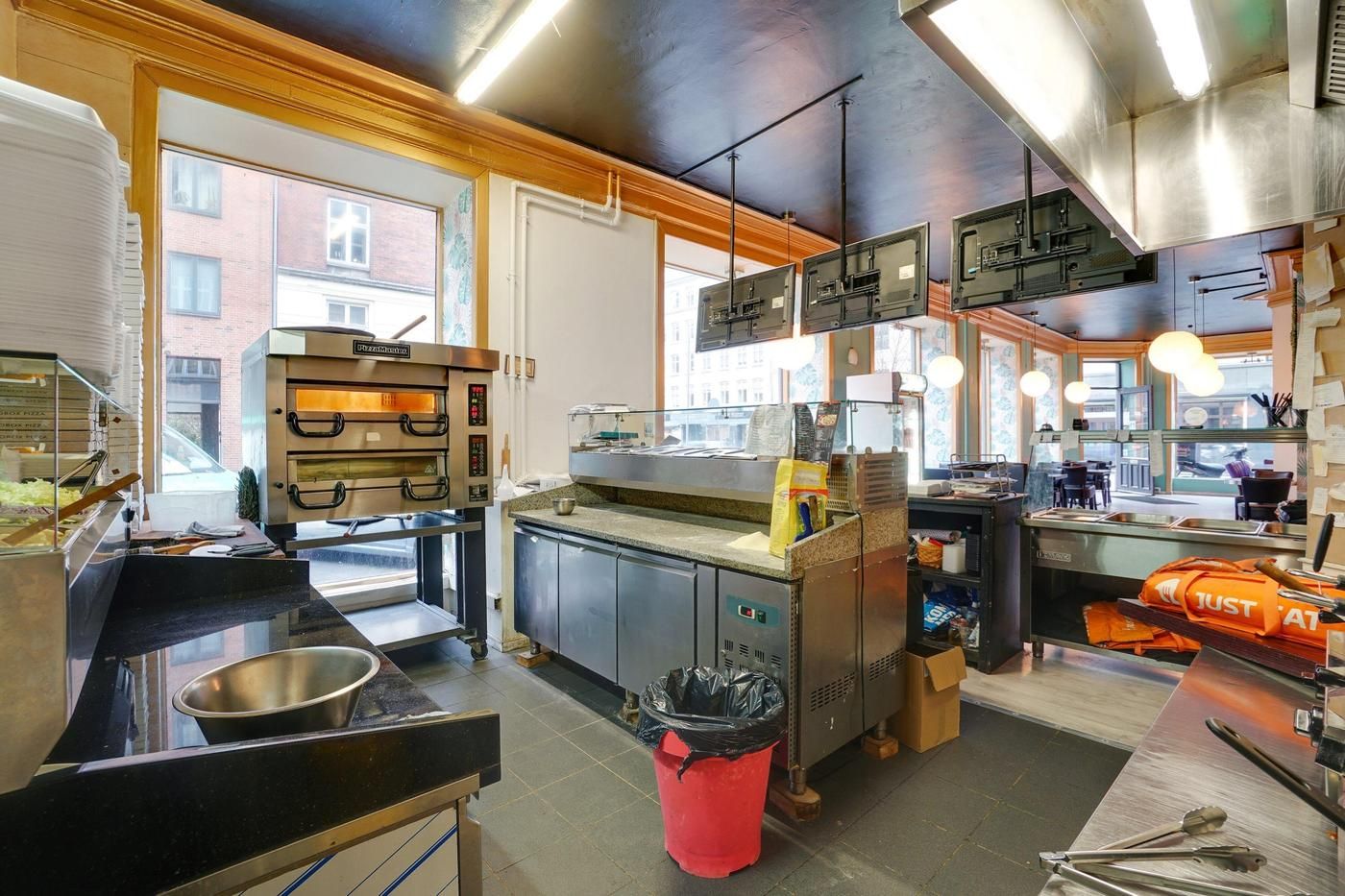 En køkken i en restaurant med ovn, køleskabe, og forskellige udstyr og redskaber