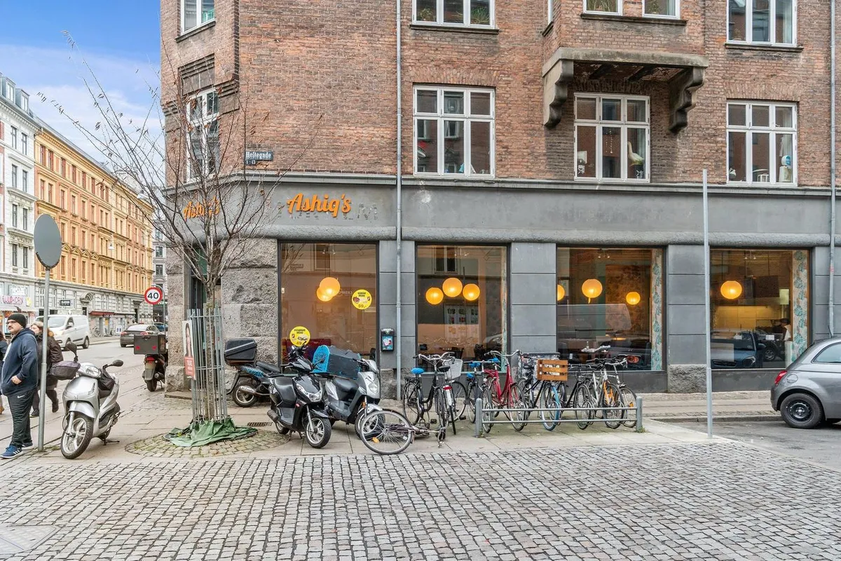 Erhvervslokaler med udsigt til Nørrebrogade og Holtegade, foran er flere cykler og motorcykler, og på gaden går mennesker