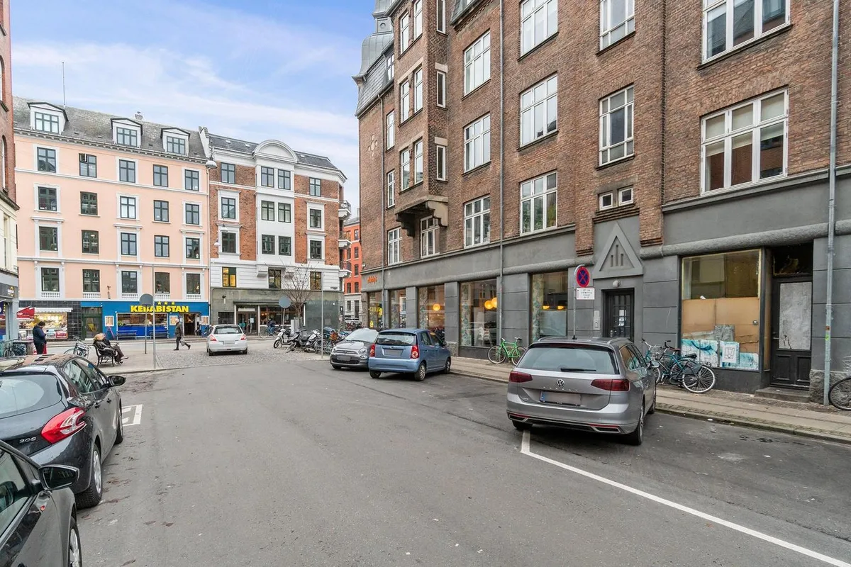 Erhvervsandel med hjørnebeliggenhed på Nørrebrogade med udsigt over gågaden og forretninger med glasvinduer