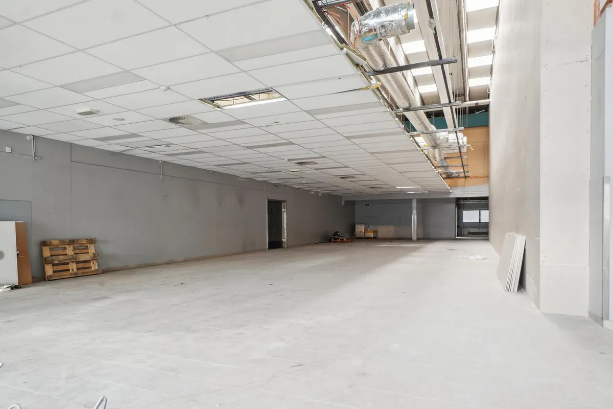 En tom lejlighed med hvide vægge og loft samt et stort åbent rum med en kasse og en dør