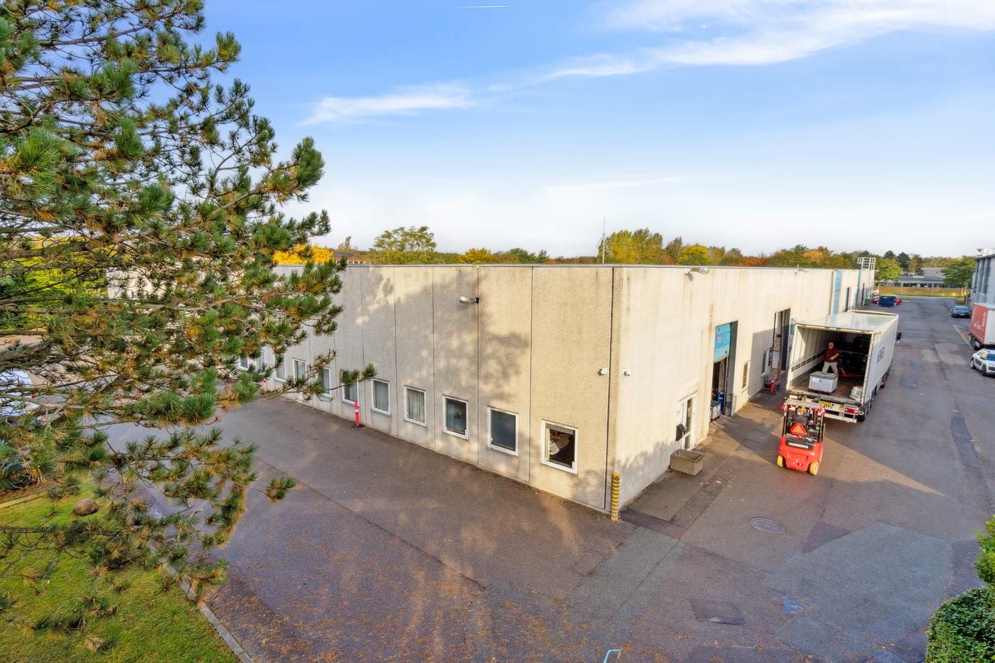 En lagerbygning med mange vinduer, og en lastbil parkeret ved en indgang