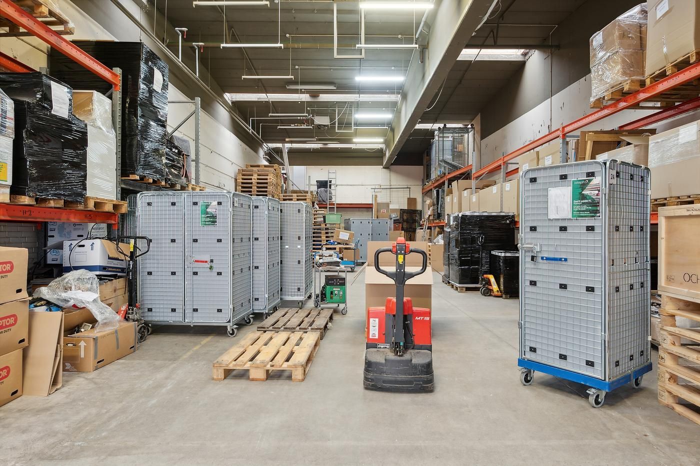 Lager med flere kassevognsstel, forskellige kasser og pallekrane i en stor lejlighed med høje lofter og vægge