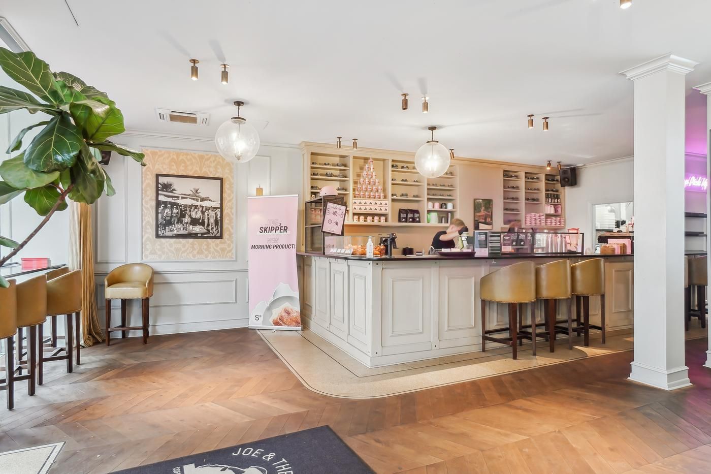 Køkken og spisestue med lyse gulve, sofaer, en bar, en plante og et banner med teksten "Mø Skipper Morning Products"