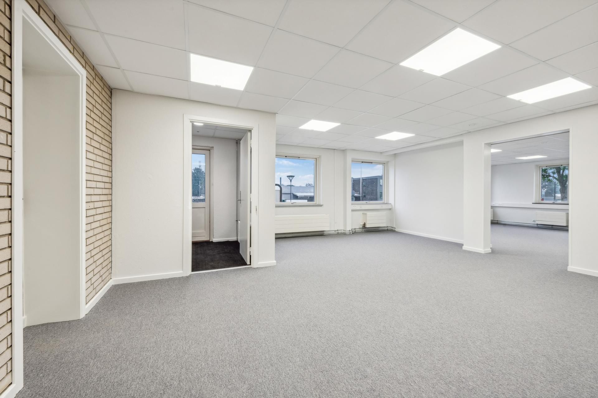 Lagerlokaler med højt til loftet og lyse vinduer med udsigt til byen og træer