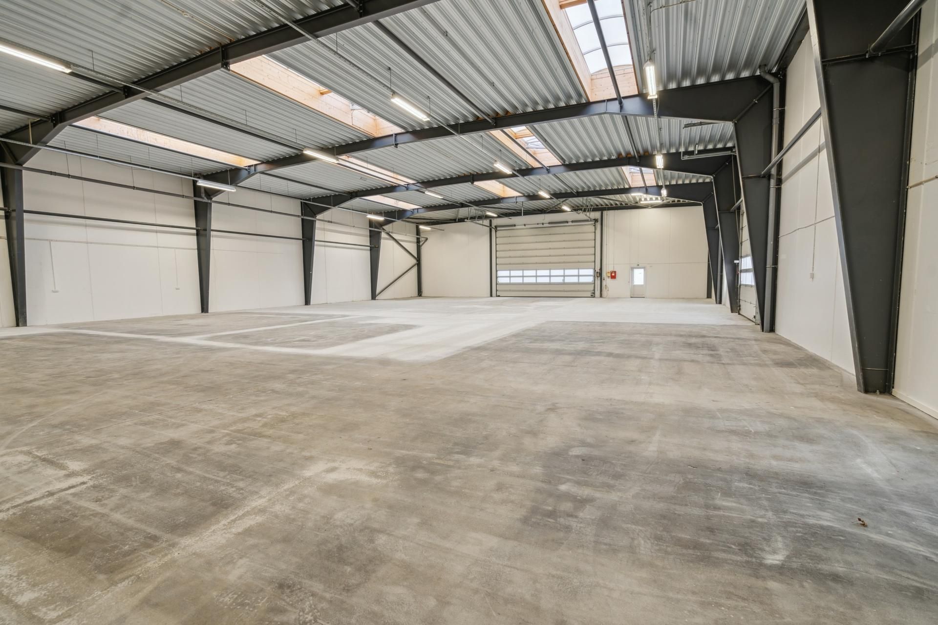 Lagerlejemål med lagerlofter og lukket garagedør, hvor gulvet er lige og erhvervsvenligt.