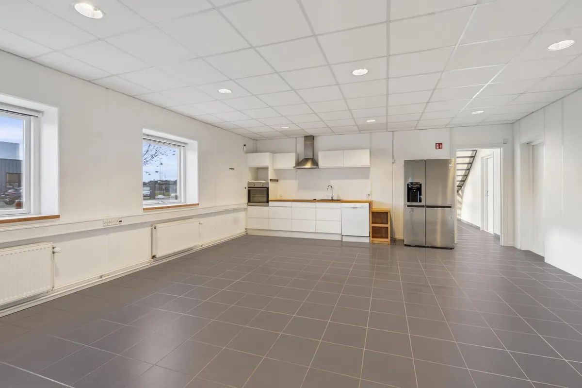 Moderne køkken med lyse hvide vægge, grå tileret gulv og hvide køkkenskabe med moderne indbygget apparater