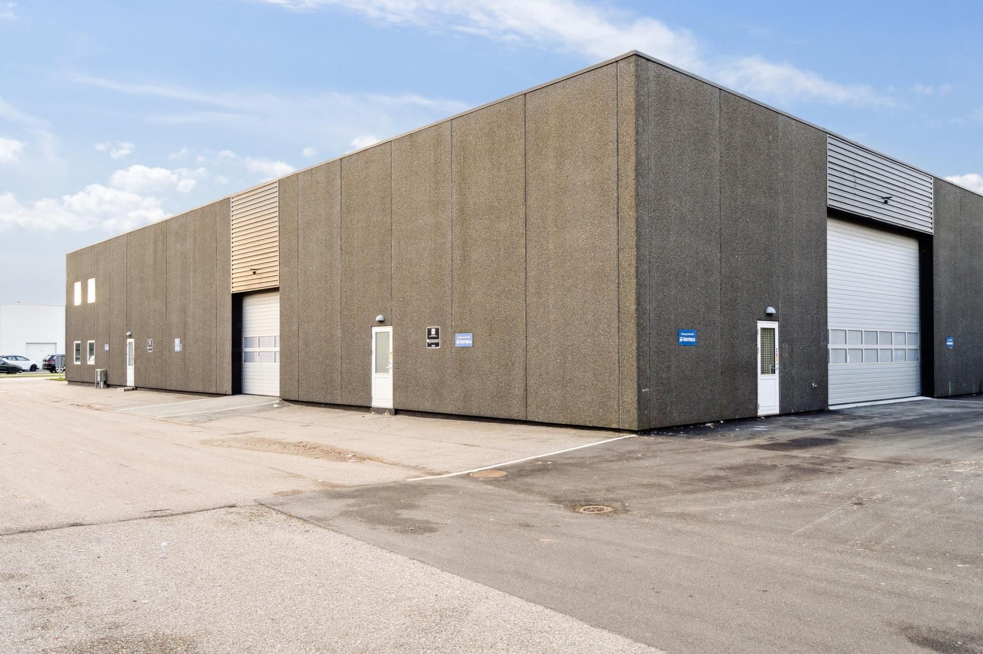 Lejemålet tilbyder en stor industribygning med to store garageindgange og to mindre døre. Bag bygningen er