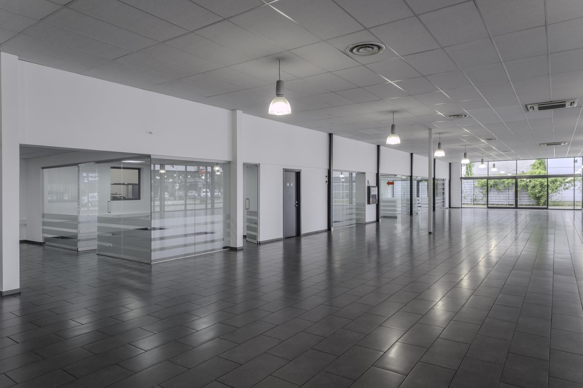 Moderne og rummelig lobby med store glasvinduer og hvide vægge samt lyskroner og store gulvfliser