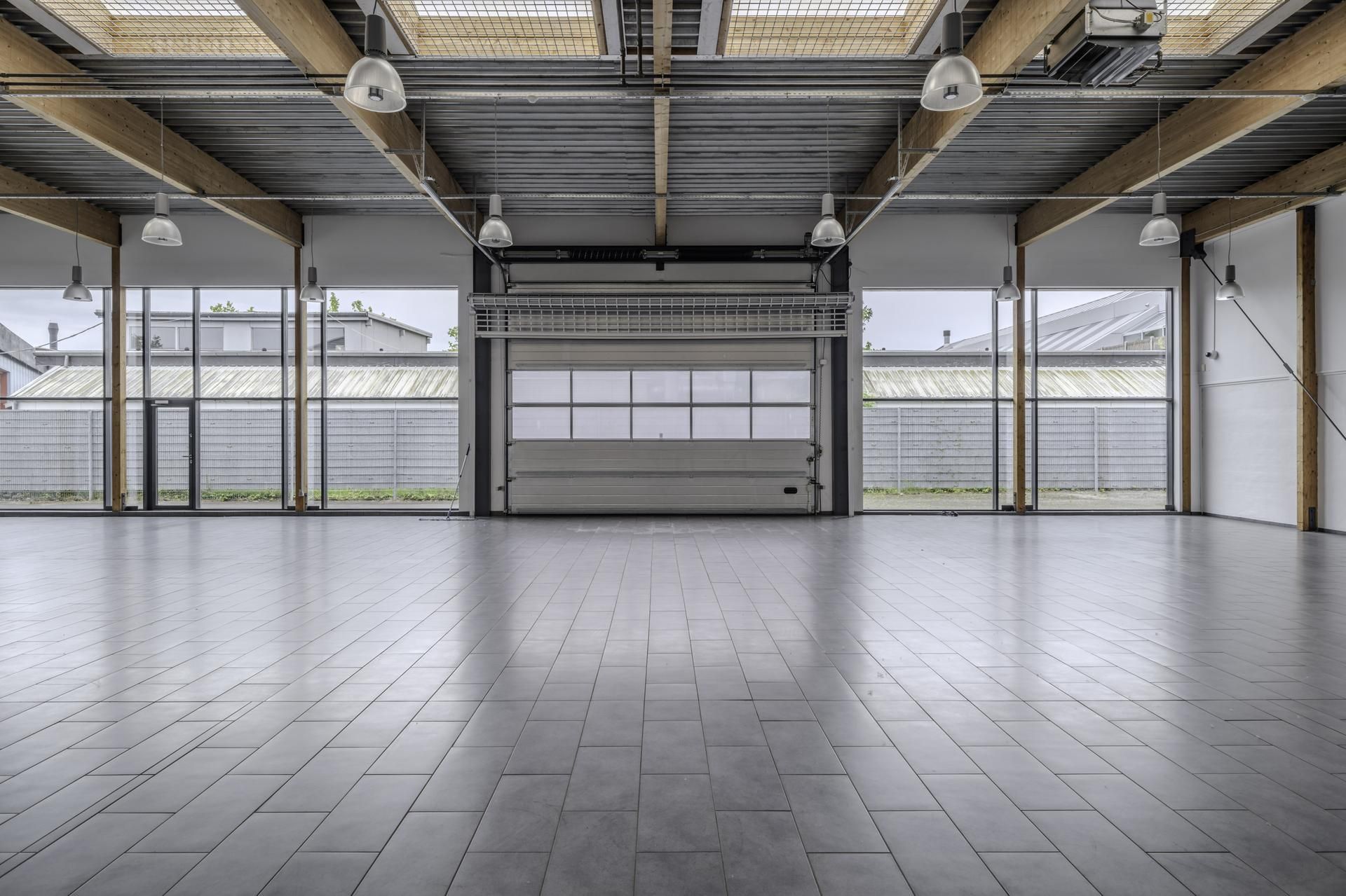 Rummelige garage med glasvægge og træbjælker, møbler og lyskatler er færdige og sammenlignes med eksisterende ejendomme