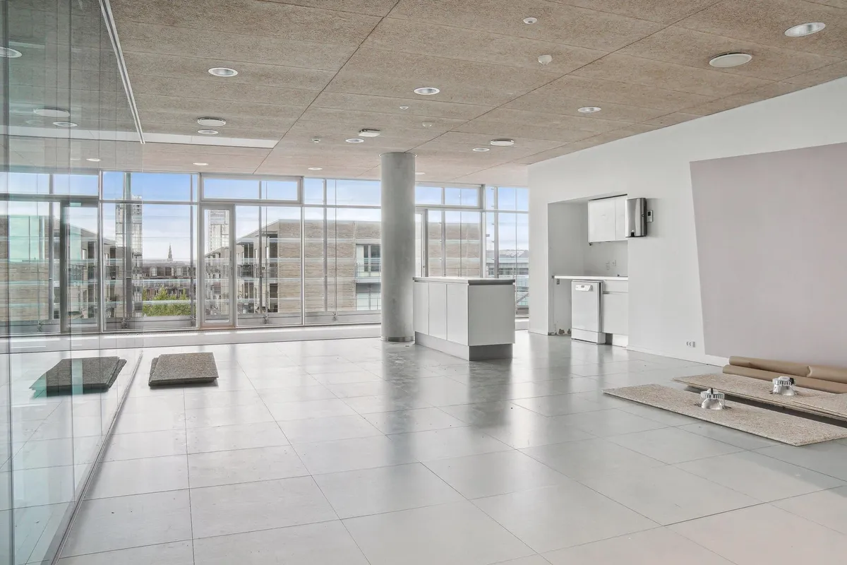 Lejlighed med glasvægge, højloft og moderne indretning. Rundt loft med runde, hvide loftslamper og gulv med hvidt