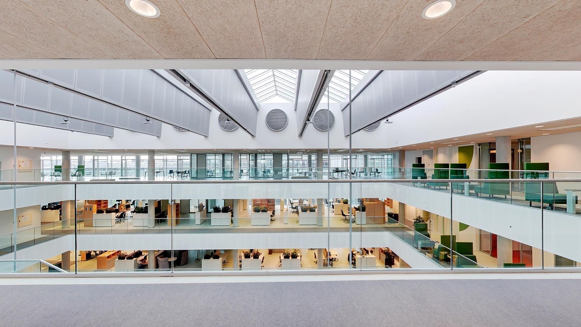 Glas lofter med udsigt til flere etager, hvor folk arbejder i de lyse kontorer