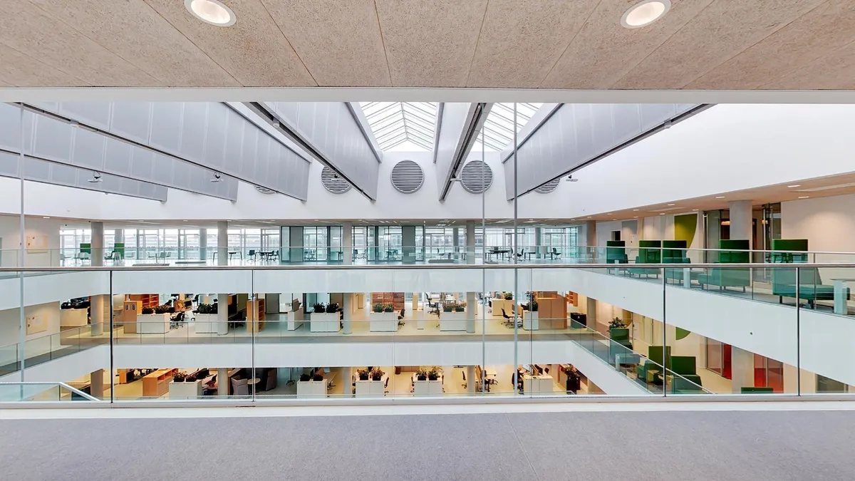Glas lofter med udsigt til flere etager, hvor folk arbejder i de lyse kontorer