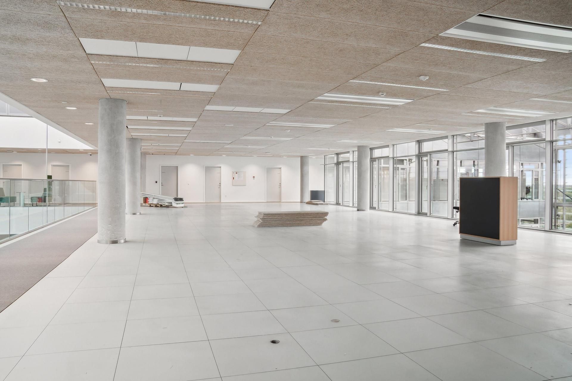 Hvidt gulv og loft med træelementer, store glasruder, flere hvide døre, træ og metalmøbler, høj teknologisk standard, fuld