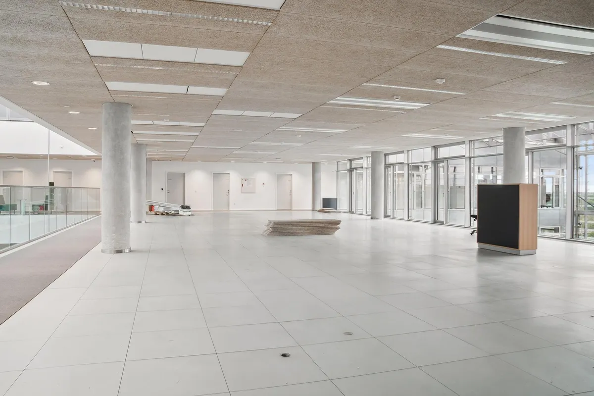 Hvidt gulv og loft med træelementer, store glasruder, flere hvide døre, træ og metalmøbler, høj teknologisk standard, fuld