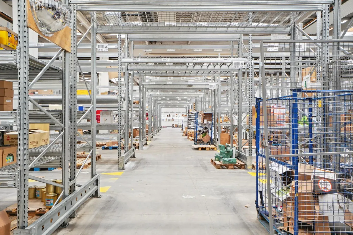 Industri- og logistikejendom med masser af lagerplads og pakket varer på lagerreoler samt pakket varer på palle.