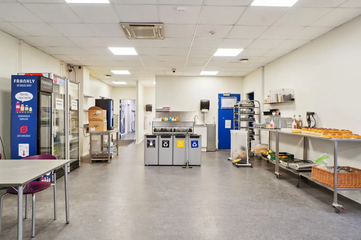 Køkken med to køleskabe, 3 opsamlingscontainere, stol, skraldspande, bord, og madkurve samt brødrister og bøfler