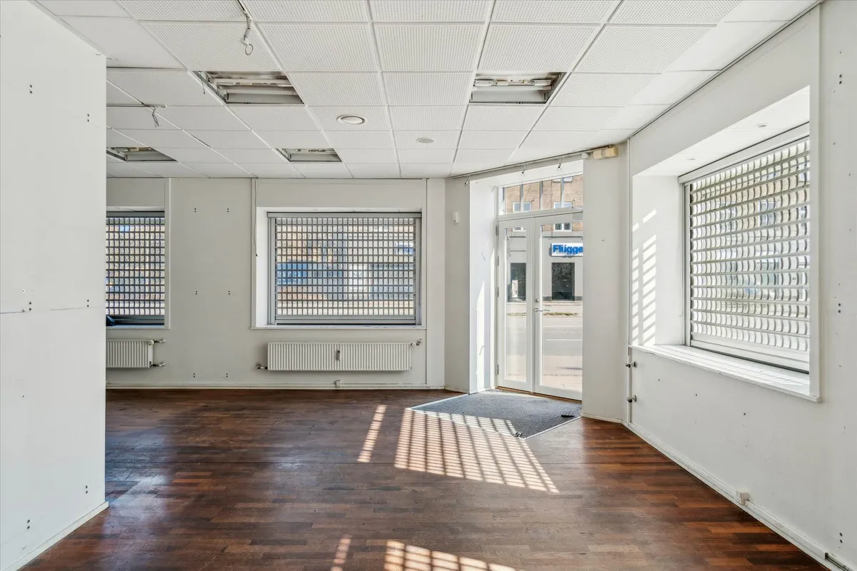 Store tomt lokale med hjørneplacering og skurvinduer, lyse og åbne områder med højt loft, trægulv og radiatorer