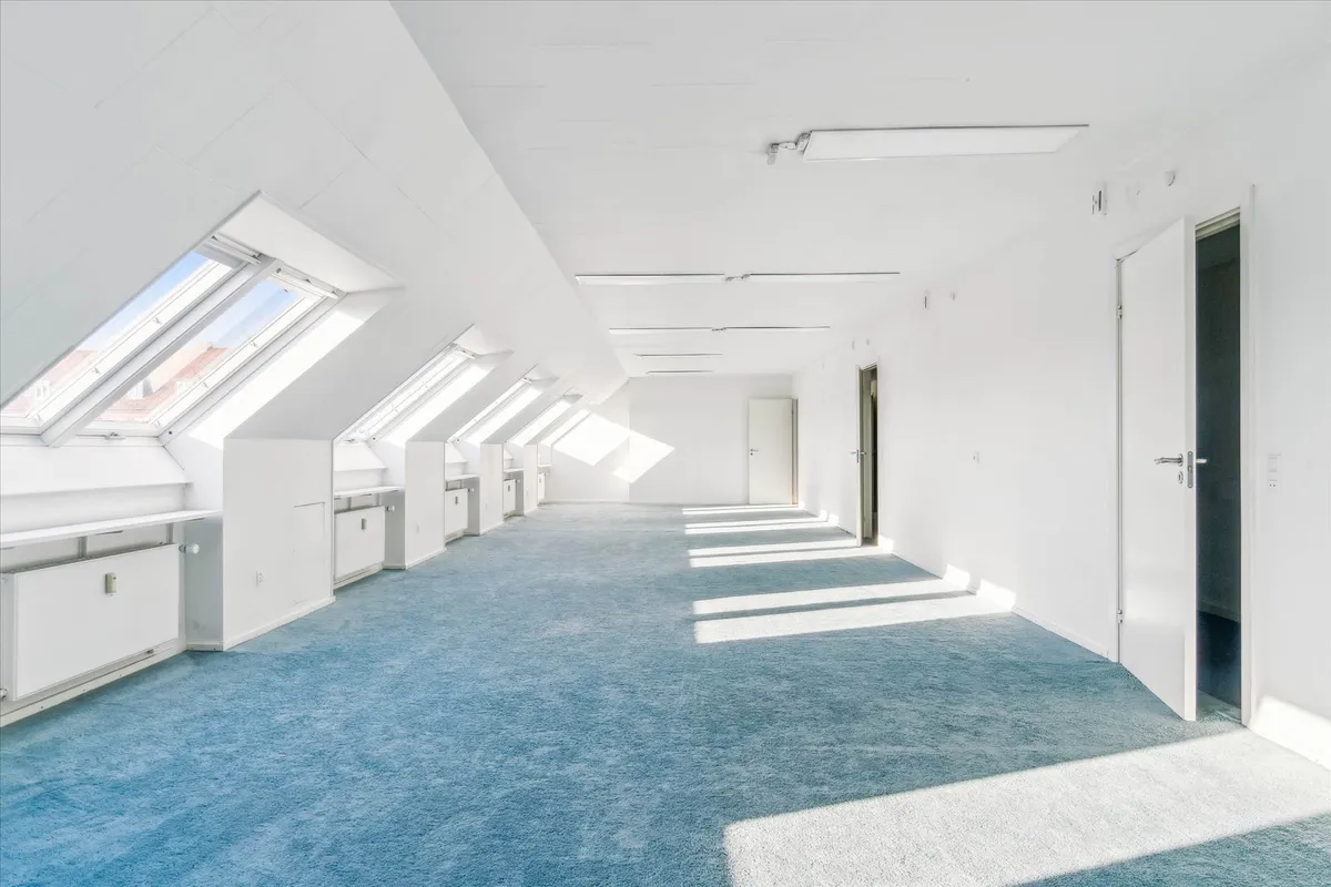 Lyst, stort kontor i hvidt og blåt, med store vinduer, hvide vægge og lyse lofter, samt lyse gulve