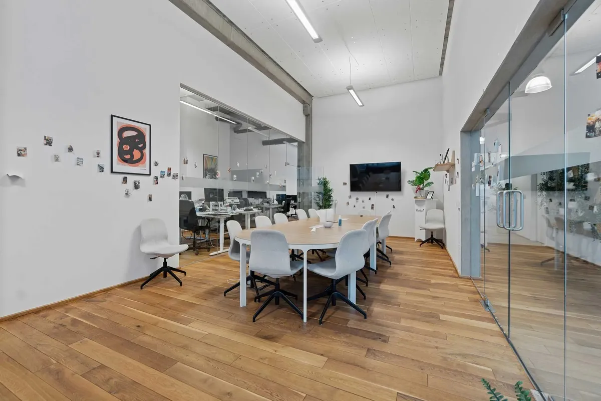 Moderne mødelokale med højt loft og lyse vægge med trægulve og store glasruder