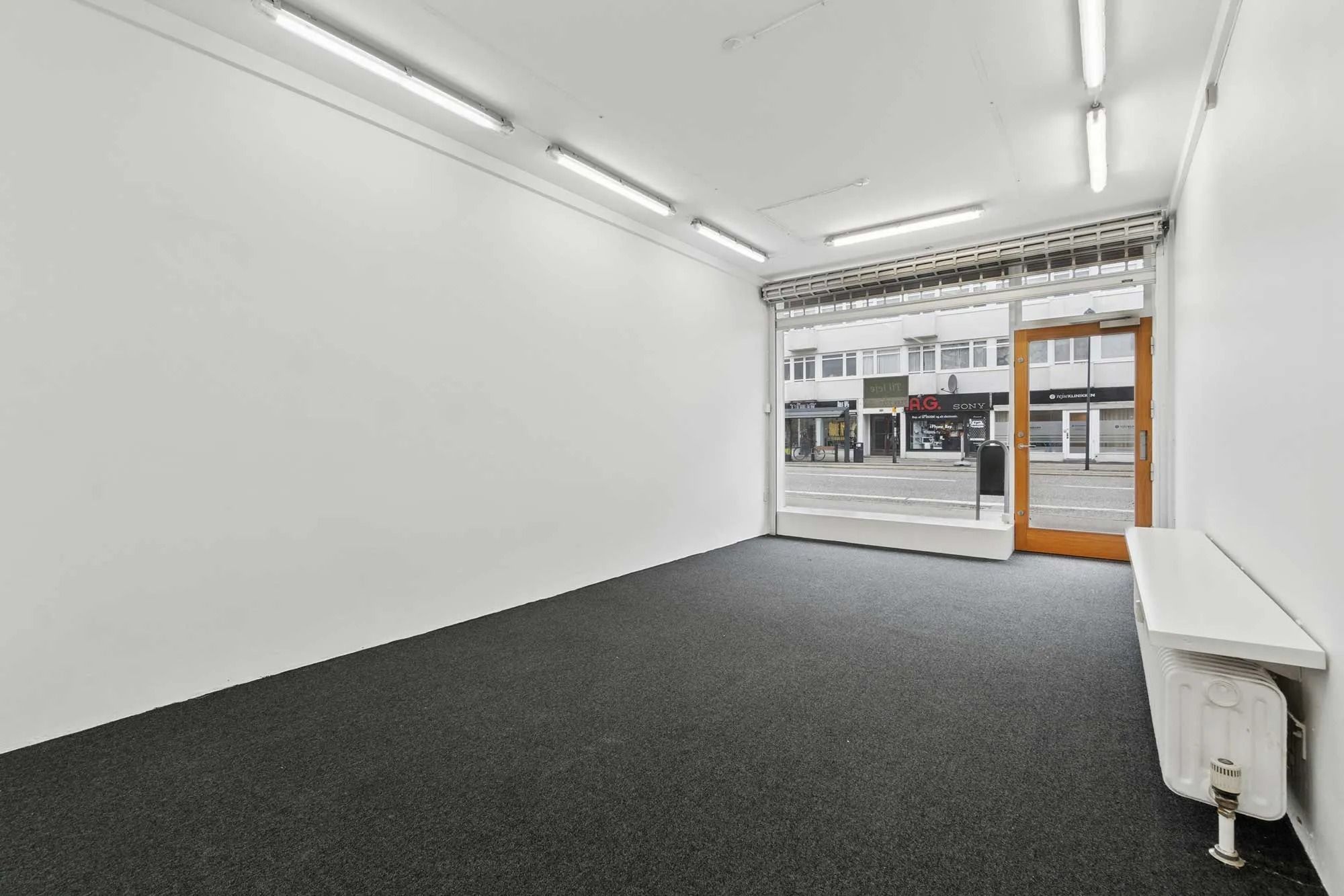 En stor og lys pop-up butik med store vinduer og en trædør til gaden