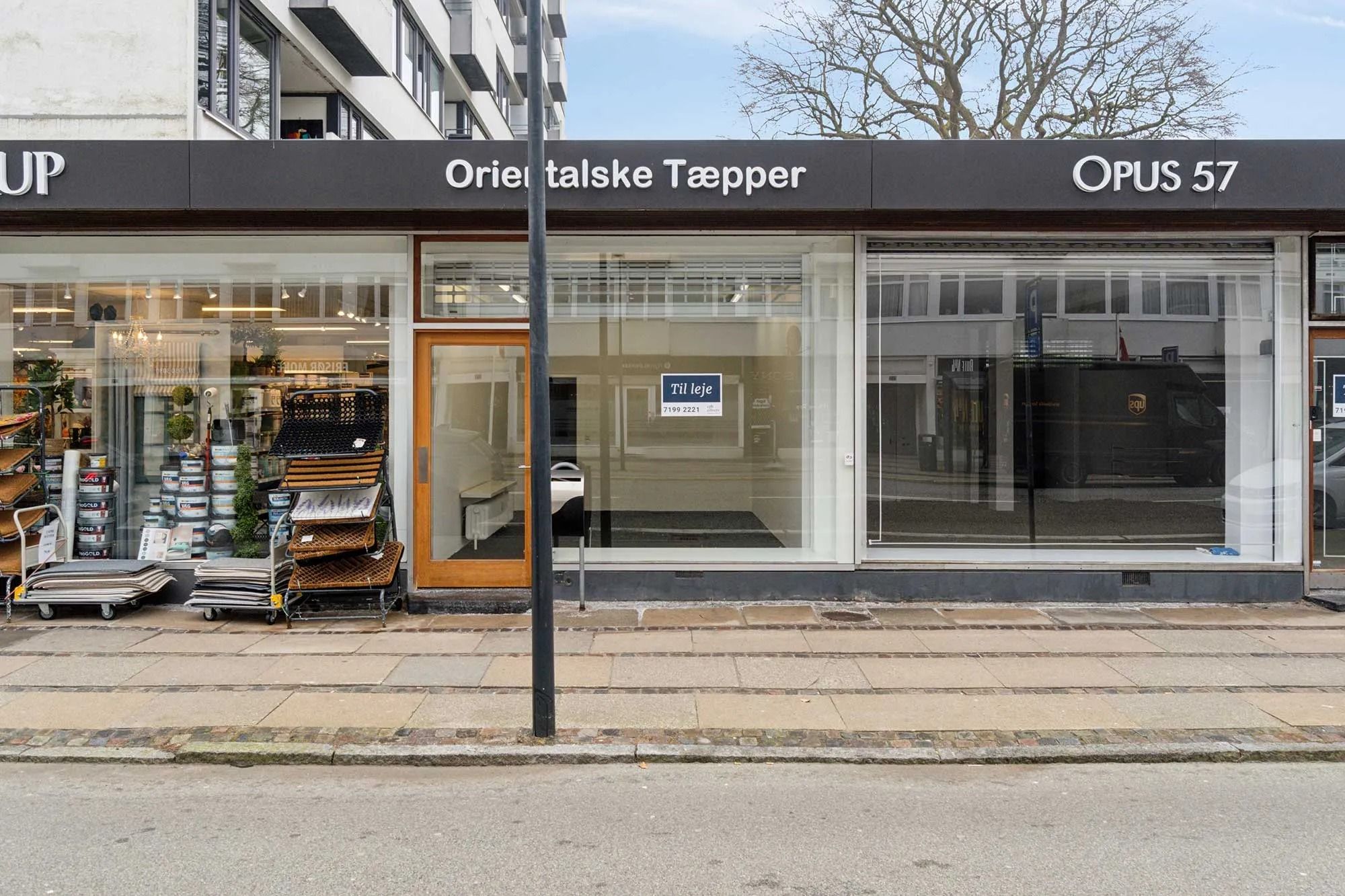 Københavnsgade med glasvinduer til leje og teksten "Til leje" og "OPUS 57" uden for butikken med nummer 7199