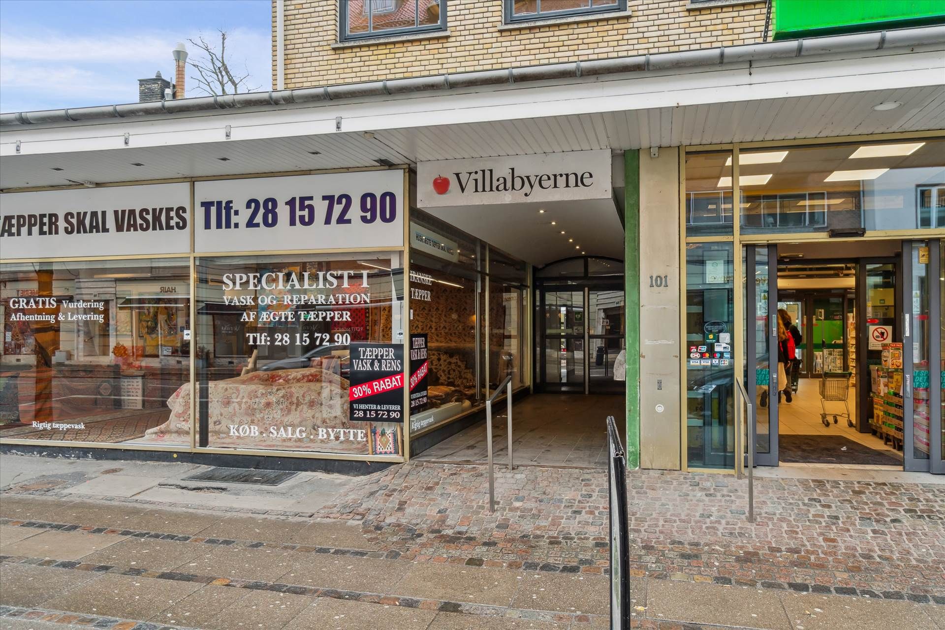 Foto af forretningslokaler med tekster, hvor den ene hedder "Specialist i vask og reparation af ægte tæpper" og den anden