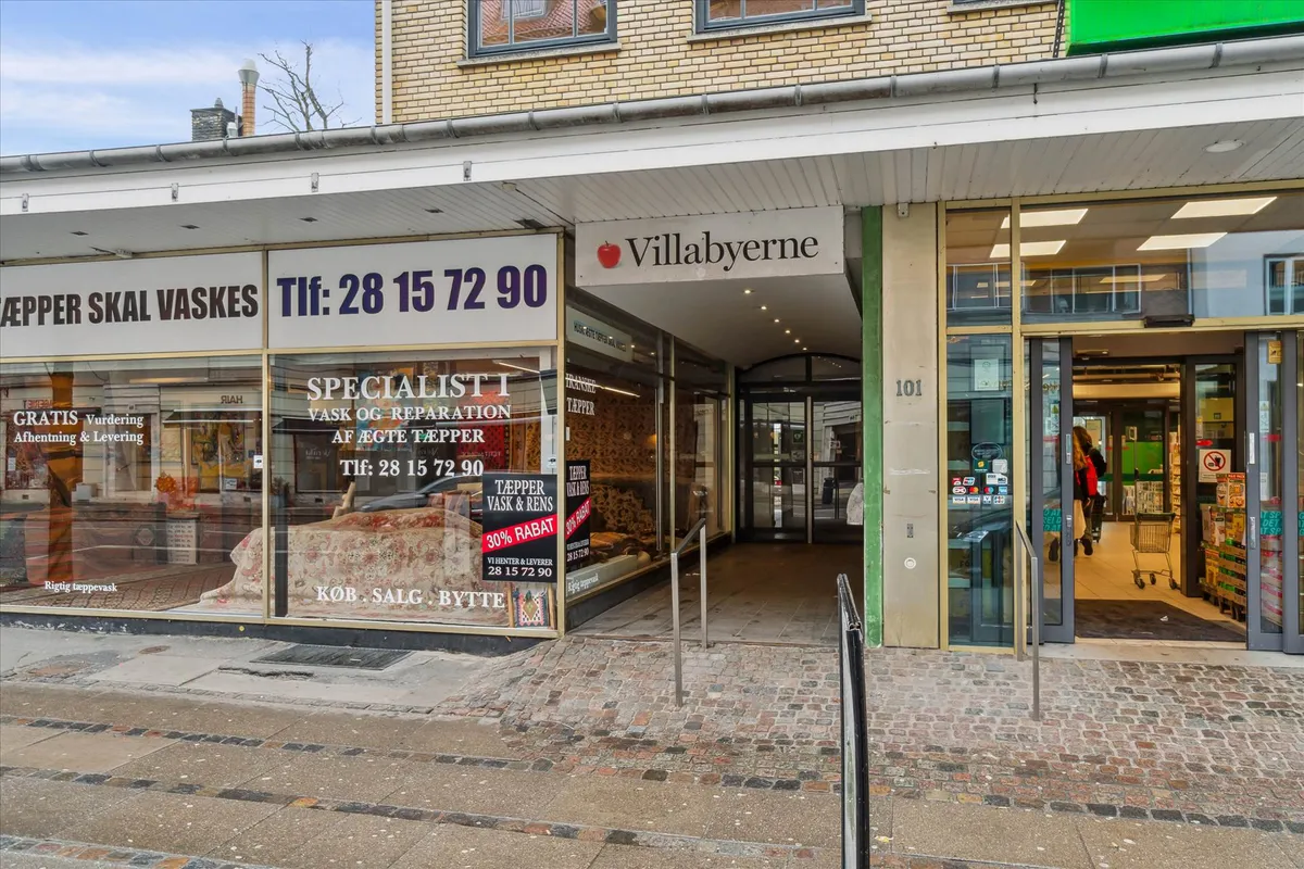 Foto af forretningslokaler med tekster, hvor den ene hedder "Specialist i vask og reparation af ægte tæpper" og den anden