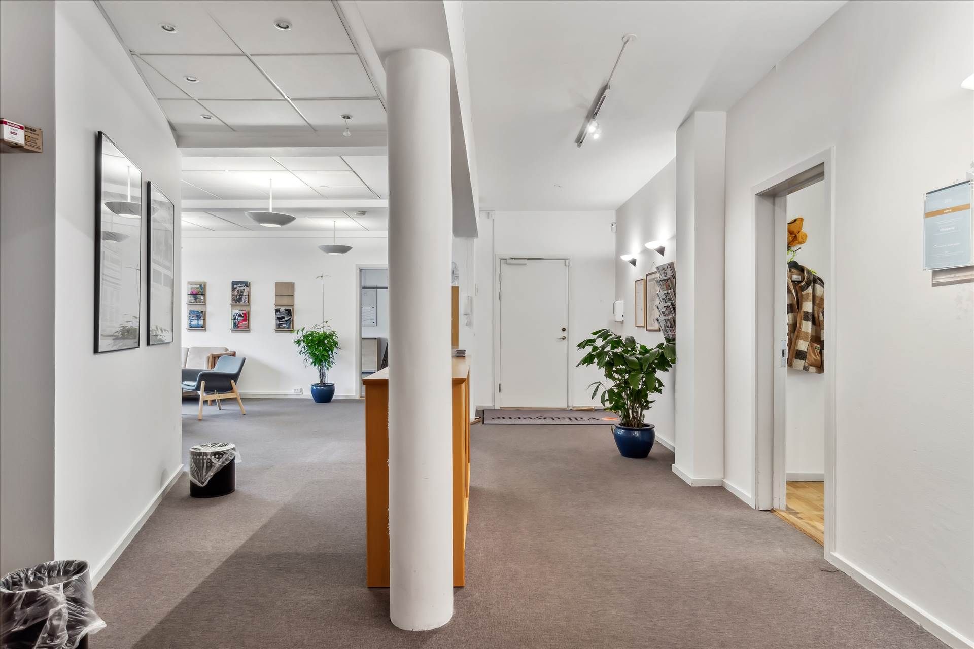 Elegant kontorlokaler i lyse og velholdte bygning med gulvbelægning og hængende plante.