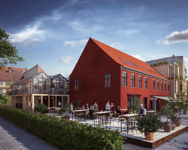 En stor rød bygning med solpaneler på taget og en rummelig gårdhave med borde og stole og grønne planter