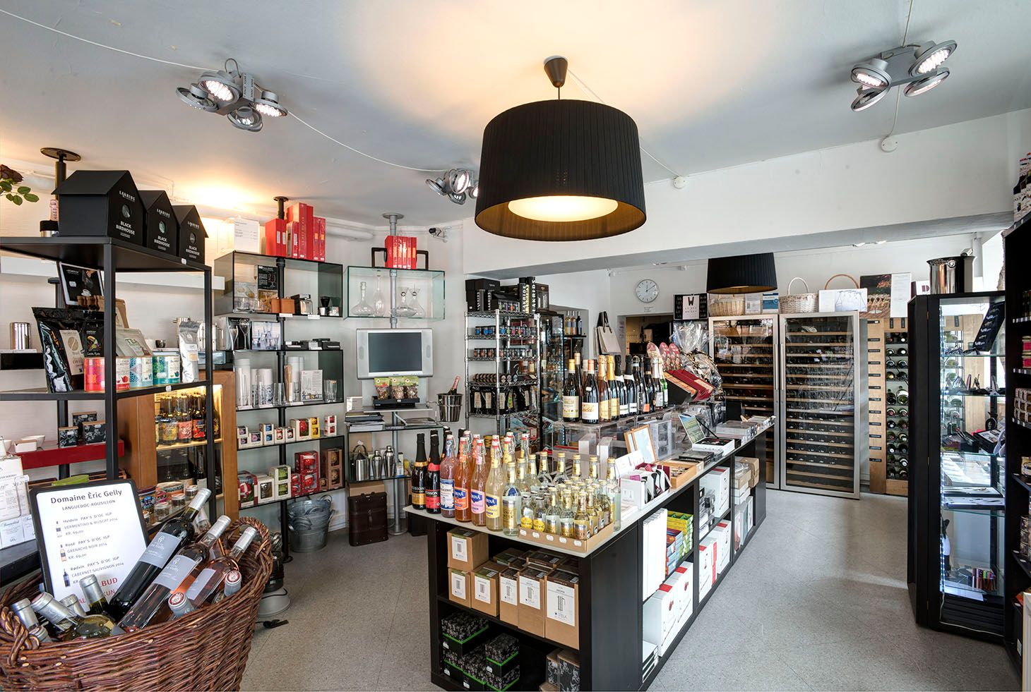 Butik med vinflasker, vinkrukker, glas og andre produkter. Lamper og ure er også synlige.