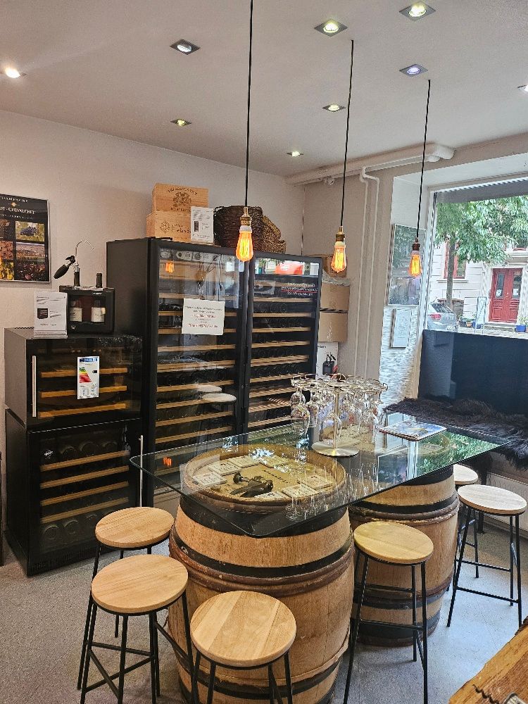 Vinbar med borde lavet af tønder og glasbord samt flere vinskabs og et vinglasholder på bordet