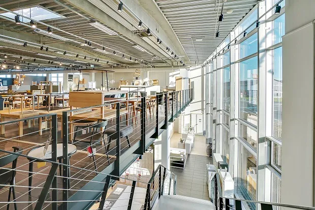 En stor salgslokal med lyse gulve og lysegule vægge samt lyse lofter og store vinduer med udsigt til byen