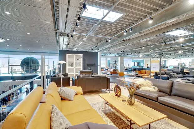 Forretningslokale med moderne møbler og lyse loftsvinduer, der skaber et lyst og åbent indtryk