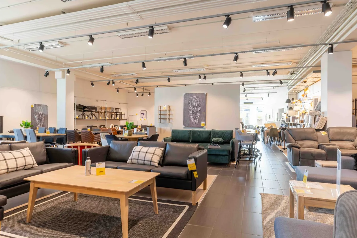 Inde i et lyst og moderne møbelforretningslokal med sofaer, stolpe og træborde, smukke lysekroner og smukke udsmykninger på