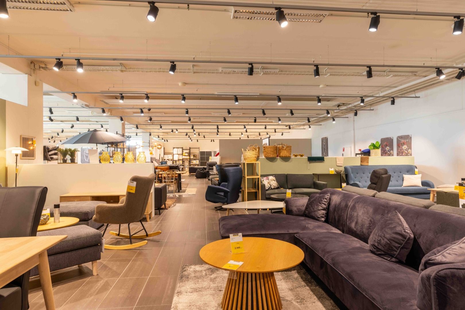 Lyst og moderne møbelforretning med forskellige sofaer, stole, træborde og andet møbeludstyr.