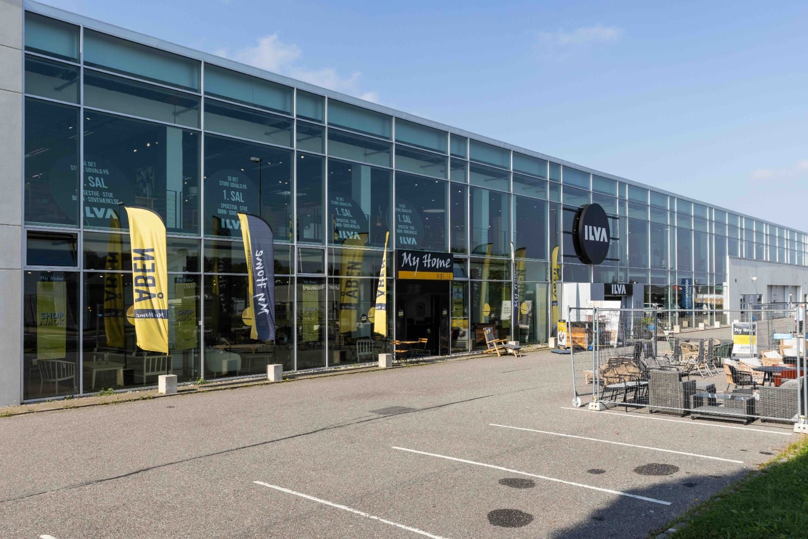 En stor, lys og moderne butik med store vinduer og lyse bannere. Butikken har store vinduer med tekst og logoer. Der er en