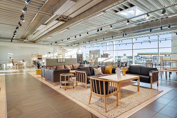 Store møbelforretning med træmøbler og lædersofaer, samt lyse loftslamper og gulvtæppe